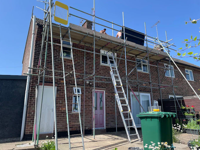 Rear-elevation scaffolding with a boarded working platform at the roofline of a brick house in York